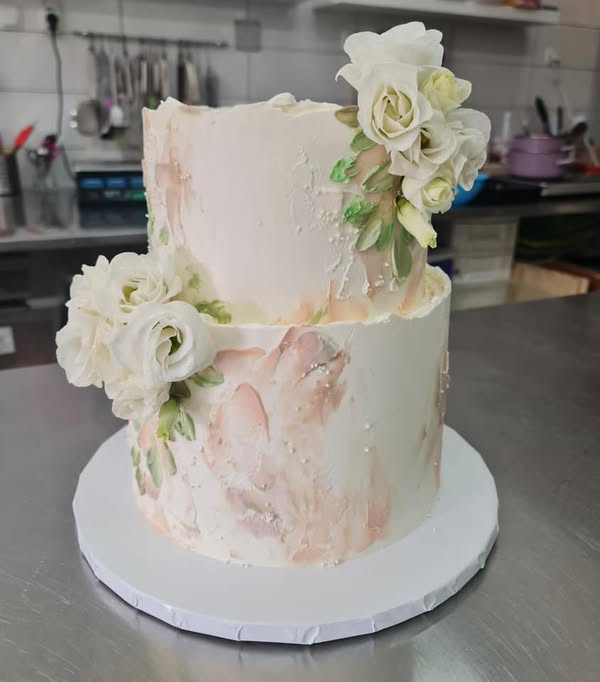 Cupcake svadbena torta na dva kata, ukrašena bijelim cvijećem i nježnim ružičastim detaljima